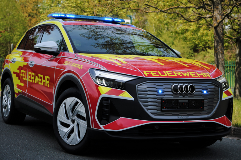 Ein Feuerwehrauto steht vor einer Gruppe von Bäumen.