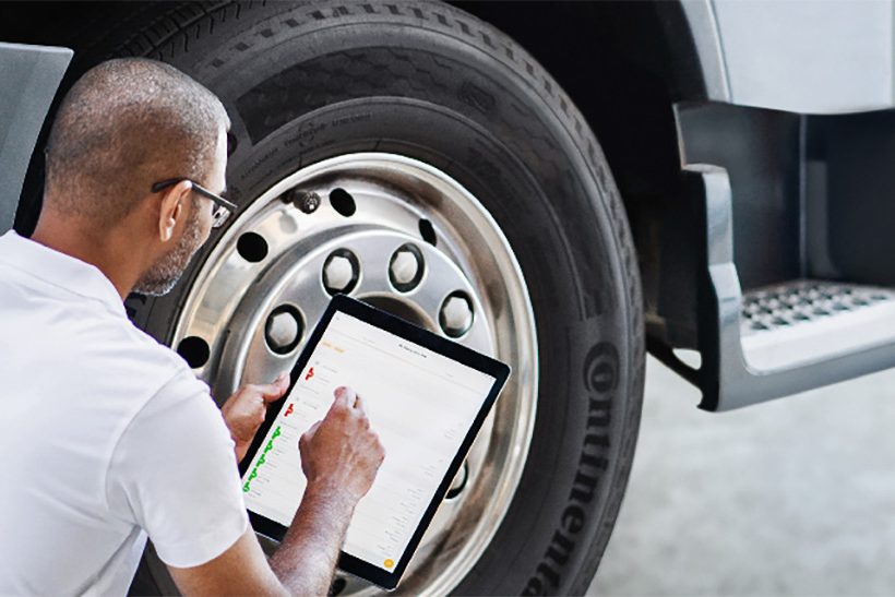 Digitales Reigenmanagement: Das Bild zeigt, wie ein Mann vor einem LKW-Reifen kniet und mit einem Tablet den Reifenzustand mittels der Software ContiConnect von Continental prüft.