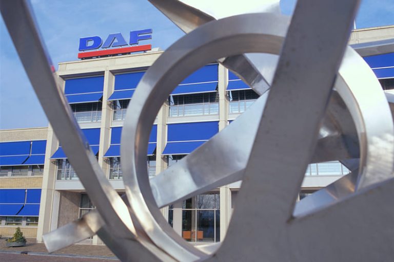 Das Bild zeigt den Firmensitz von DAF Trucks. Im Vordergrund sind Teile eines Kunstwerks zu sehen.