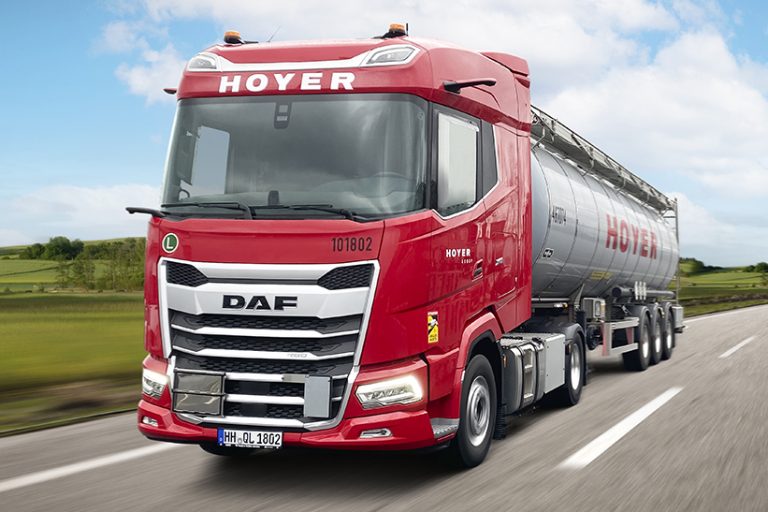 Zu sehen ist ein LKW mit einer roten Zugmaschine während der Fahrt. Es handelt sich dabei um einen neuen DAF XG 480 von Hoyer.