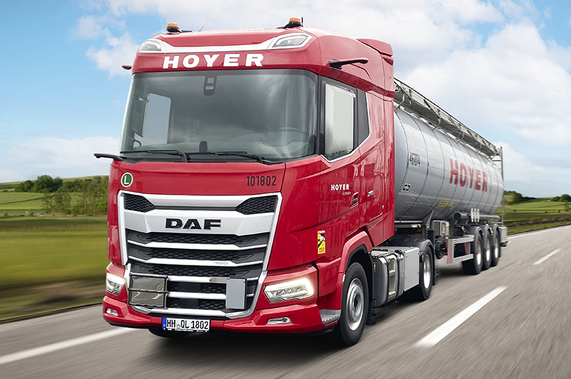 Zu sehen ist ein LKW mit einer roten Zugmaschine während der Fahrt. Es handelt sich dabei um einen neuen DAF XG 480 von Hoyer.