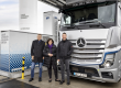 Die sLH2-Technologie bringt Linde und Daimler Truck zusammen, die zusammen die erste öffentliche Tankstelle betreiben. Das Bild zeigt diese Tankstelle ebenso wie einen silbernen Truck mit Stern und drei Menschen, die vor diesem Fahrzeug stehen.