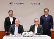Hyundai liefert vollelektrisches leichtes Nutzfahrzeug an Iveco in Europa. Das Bild zeigt das Führungspersonal beider Häuser bei der feierlichen Unterschrift. Zwei Männer sitzen an einem Tisch, vor sich die Vertragsunterlagen und zwischen ihnen ein Strauß Blumen. Hinter ihnen stehen zwei weitere Männer.
