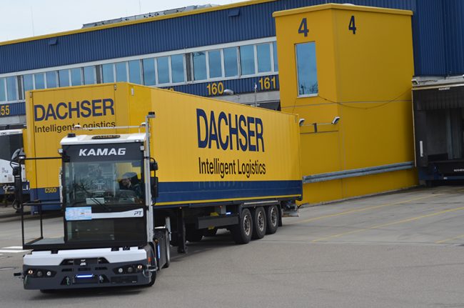 Das Bild zeigt einen Anhänger von Dachser, der auf einem Betriebsgeläne rangiert wird.
