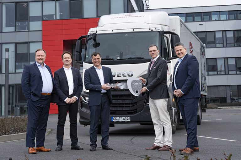 Das Bild zeigt fünf Männer vor einem Iveco-LKW, der von Transgourmet Deutschland betrieben wird. Zwei der Männer halten einen überdimensionalen Schlüssel in der Hand.