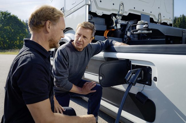 Das Bild zeigt zwei Männer an einem Elektro-LKW. Sie reden über die die neue E-Infrastruktur von Daimler Truck unter dem neuen Etikett TruckCharge.