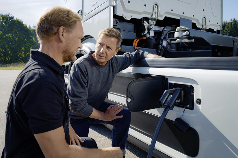 24DT125_001 Das Bild zeigt zwei Männer an einem Elektro-LKW. Sie reden über die die neue E-Infrastruktur von Daimler Truck unter dem neuen Etikett TruckCharge.