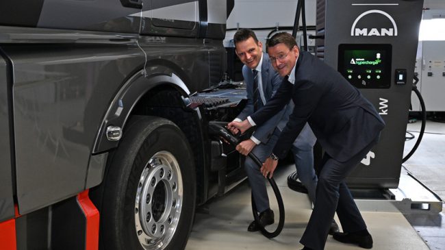 Führungskräfte von Eon und Man simulieren das Elektroladen eines Elektro-Lkw.