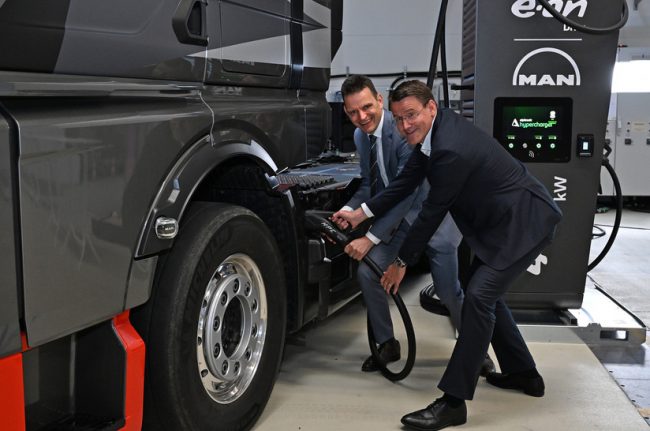 Führungskräfte von Eon und Man simulieren das Elektroladen eines Elektro-Lkw.