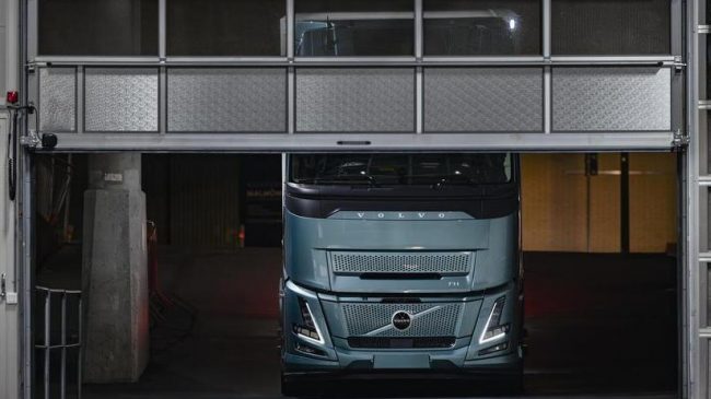Das Bild zeigt einen Volvo FH Electric, der innerhalb einer Halle vor einem halbgeöffneten Tor steht.
